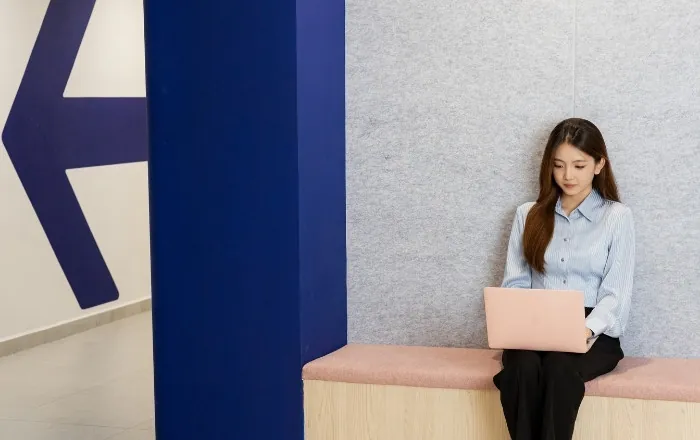 모나쉬 대학교 말레이시아 벽 앞 벤치에서 노트북을 보는 학생