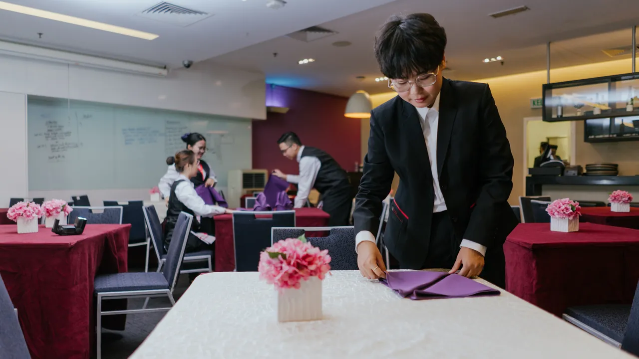 테일러스 대학교 실습 레스토랑에서 테이블을 세팅하는 학생